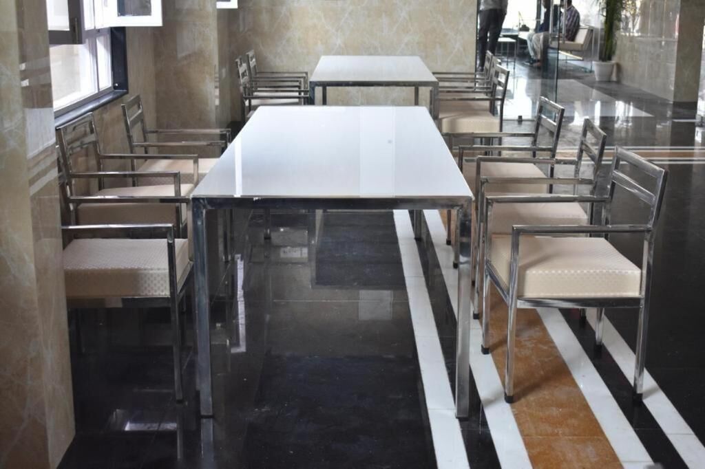 Un comedor moderno con una mesa larga y sillas, suelo pulido y pared de mármol.
