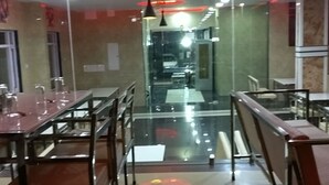 A modern restaurant with glass partitions, metal furniture, and red ambient lighting. - Hotel Royal Country Club (Pindra)