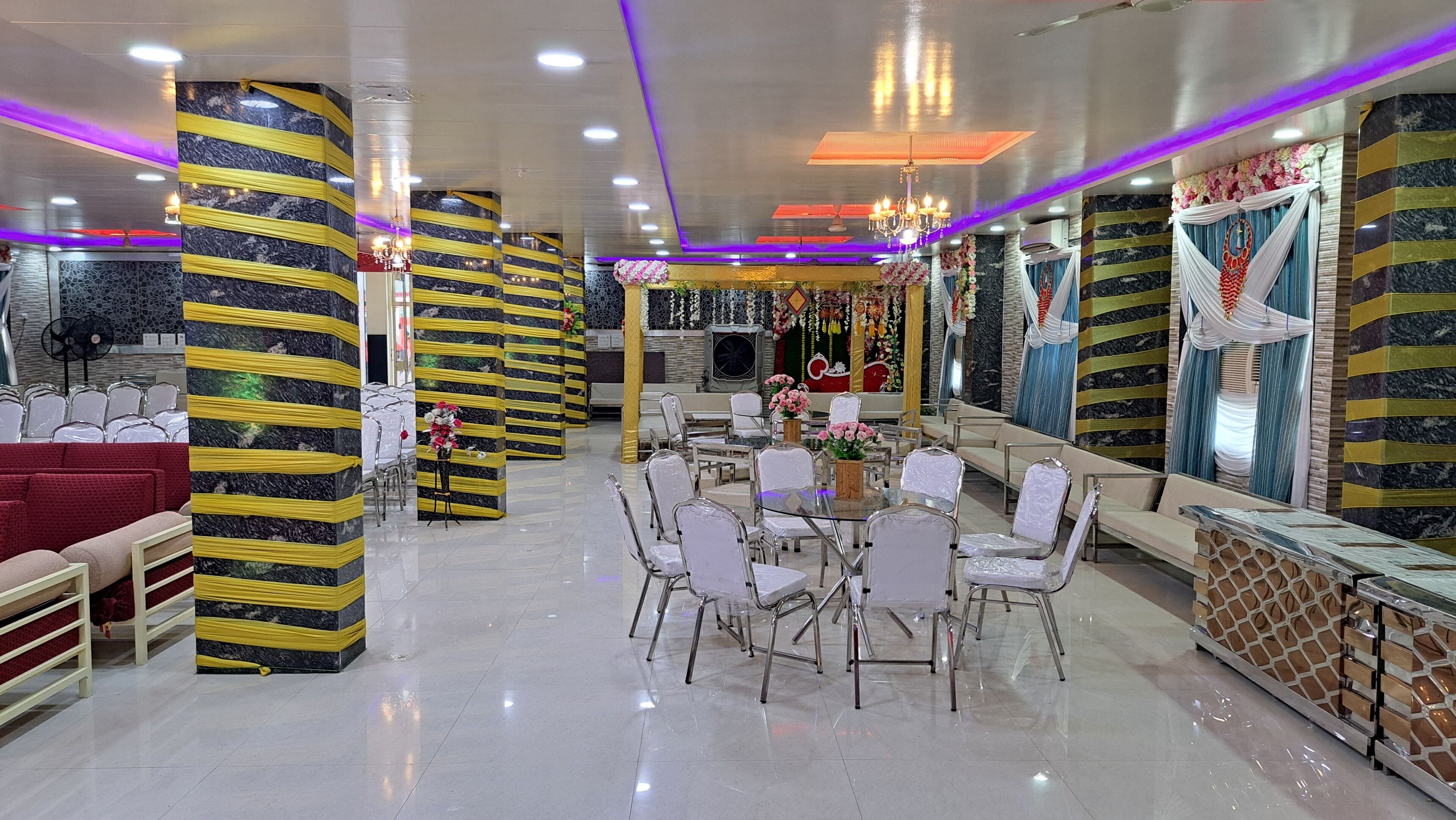 Un amplio vestíbulo de hotel con zona de comedor central, diversas disposiciones de asientos y elementos decorativos.