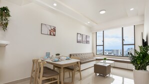 A modern living room with a dining area, large windows, and a city view. - Macy Studio Apartment (Ho Chi Minh City)