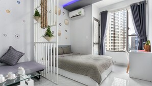 A modern bedroom with a bed, a glass table with tea set, a white desk, and a window with curtains. - Macy Studio Apartment (Ho Chi Minh City)