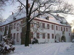 Un edificio grande e histórico con numerosas ventanas y un techo cubierto de nieve.