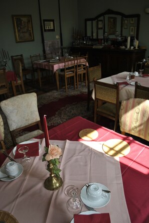 Un comedor con mesas dispuestas para una comida, con un florero con flores, platos y cubiertos.