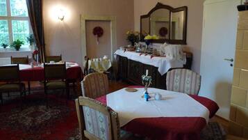 Une salle à manger avec une table dressée pour quatre personnes, un miroir au-dessus de la table et une porte sur la droite.