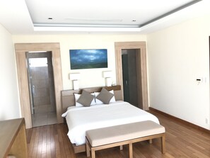 A modern bedroom with a large bed, wooden floor, and a painting on the wall. - Ocean Resort 3 Bedrooms Danang Living (Da Nang)