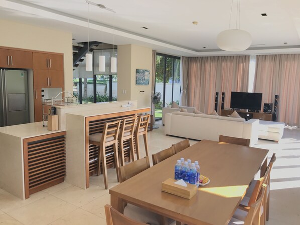 A modern living space with a kitchen, dining area, and a large sofa.