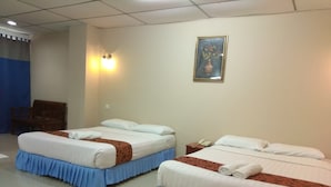 Een hotelkamer met twee bedden, elk voorzien van witte lakens en blauwe lopers. Aan de muur hangt een schilderij en op het nachtkastje staat een telefoon.