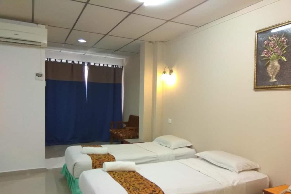 A hotel room with two beds, a chair, a desk, and a painting on the wall.