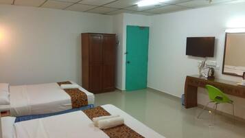 A hotel room with two beds, a desk with a chair, a television, and a green door.