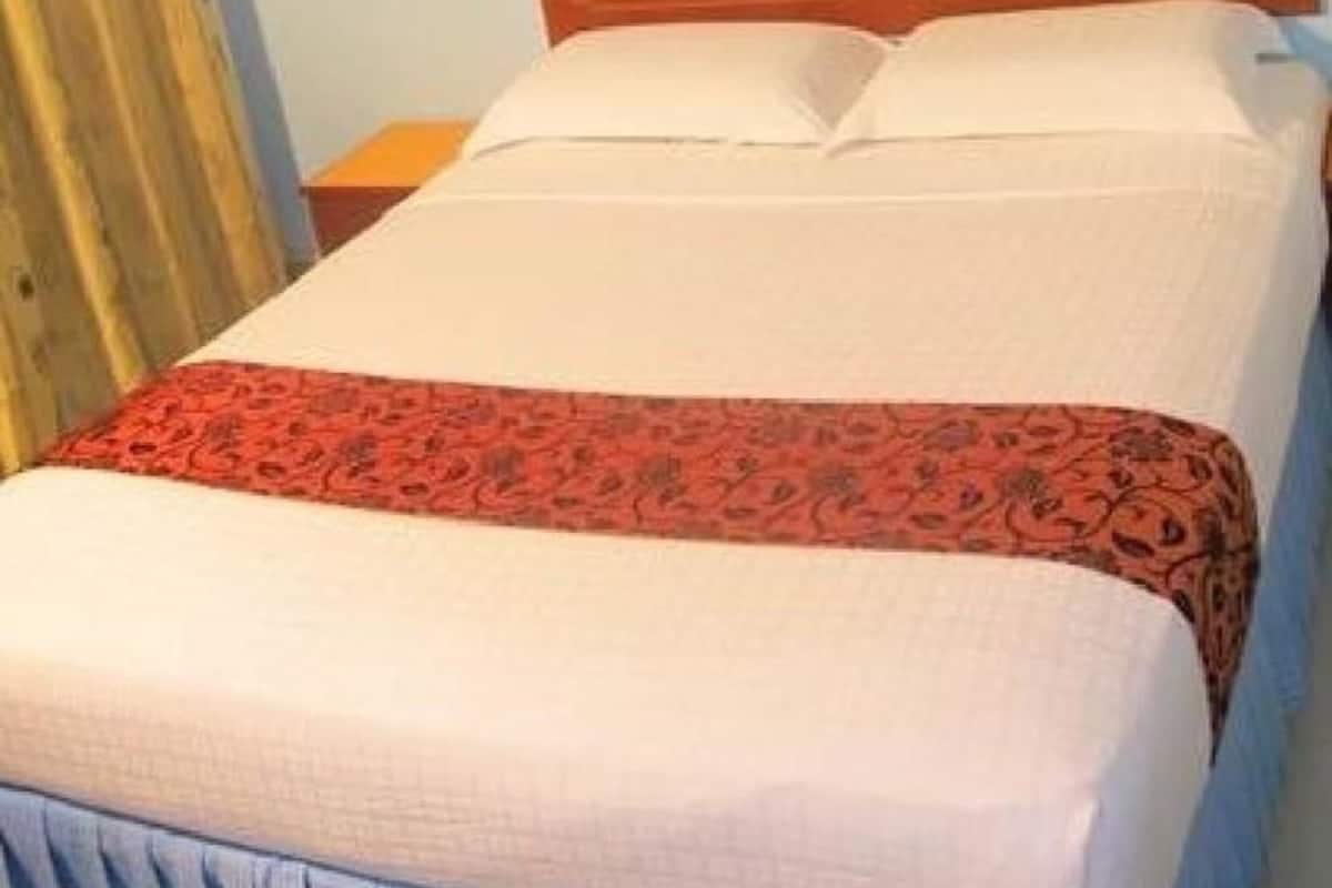 A bed with a white mattress and a red patterned bedspread.