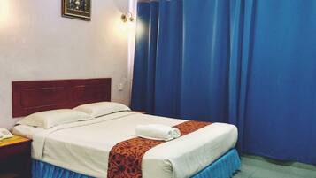 A hotel room with a bed, a nightstand, a telephone, and a wall-mounted light fixture.