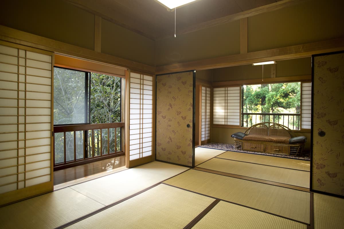 Ein traditioneller japanischer Raum mit Tatami-Bodenbelag, Schiebetüren und einem niedrigen hölzernen Bett.