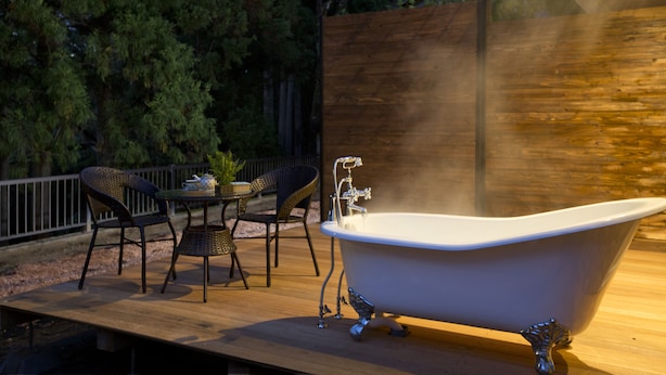 A wooden deck with a freestanding bathtub, wicker chairs, and a table with a potted plant. - Chambre d'hôte  Étoile et fées (Komatsu)