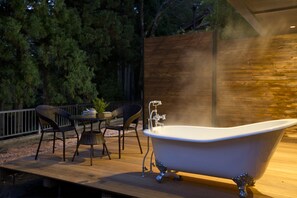 A wooden deck with a freestanding bathtub, wicker chairs, and a table with a potted plant. - Chambre d'hôte  Étoile et fées (Komatsu)