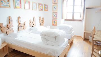 A bedroom with a wooden bed, white bedding, a wooden dresser, a wooden chair, and a window with natural light.