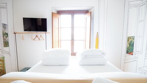 A hotel room with a bed, two towels, a TV, and a painting on the wall. - Ostello Bello Assisi Bevagna (Bevagna)