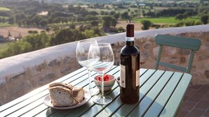 A table with a bottle of wine, two glasses, a bowl of strawberries, and a plate of bread on a terrace overlooking a scenic landscape. - Ostello Bello Assisi Bevagna (Bevagna)