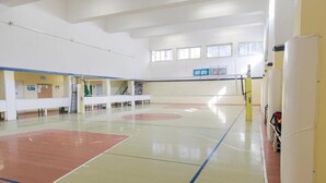 An indoor sports hall with a volleyball net, padded seating, and a basketball court. - Casa per ferie Don Orione Palermo (Palermo)