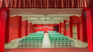 A theater with red walls, green chairs, and a stage. - Casa per ferie Don Orione Palermo (Palermo)