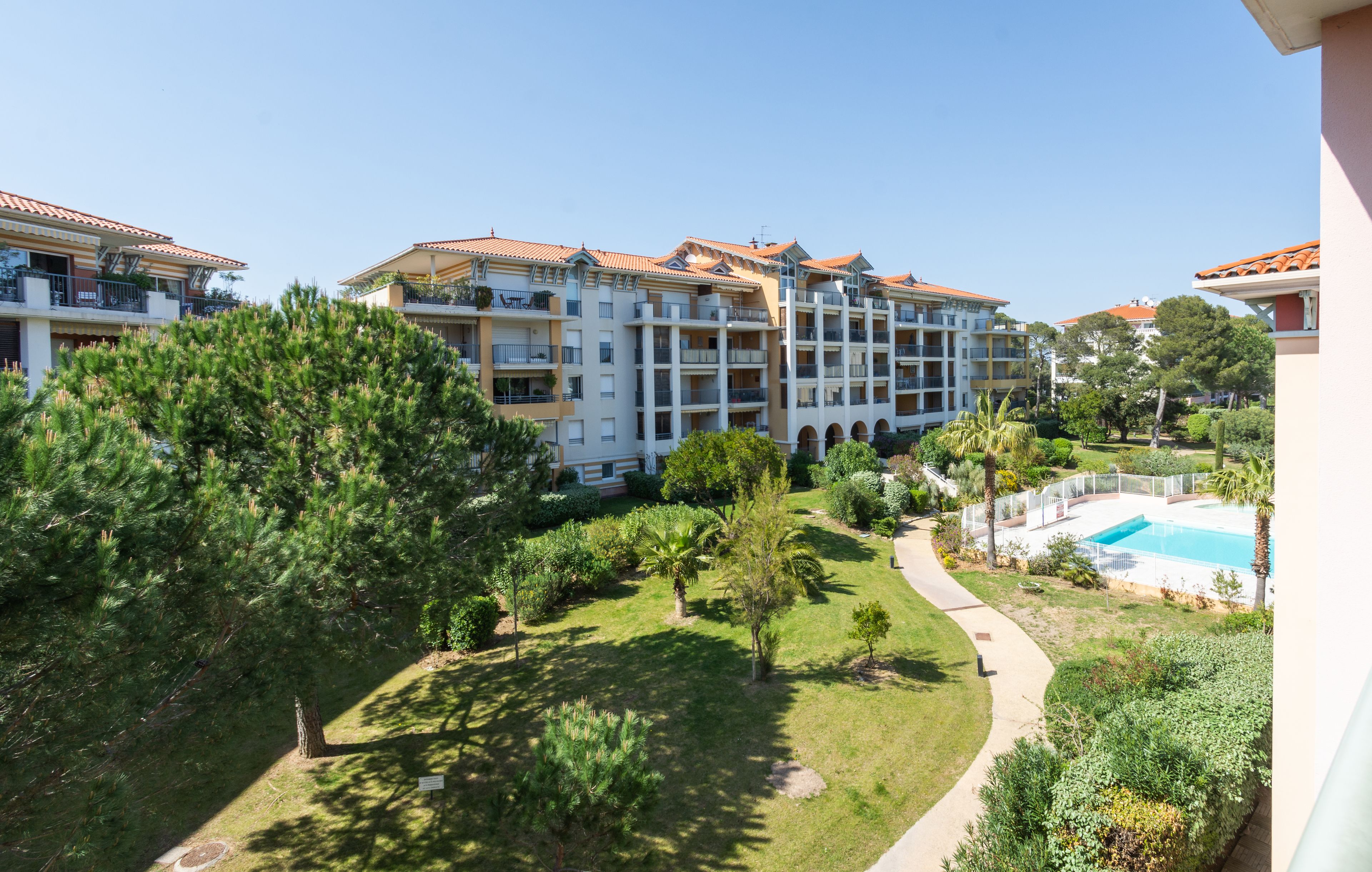 Un hotel de varios pisos con balcones, piscina y un jardín bien cuidado.
