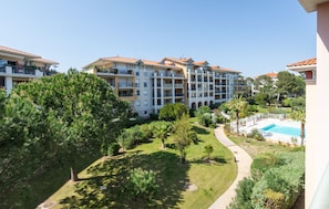 Un hotel de varios pisos con balcones, piscina y un jardín bien cuidado.