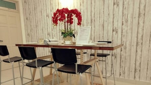 A dining area with a wooden table, black chairs, and a potted red orchid.