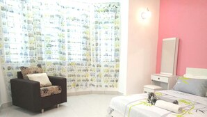 A bedroom with a bed, a chair, a bedside table, a mirror, and a window with curtains.