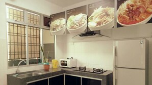 A kitchen with a gas stove, microwave, and a refrigerator. There are potted plants on the counter and a window with a view.