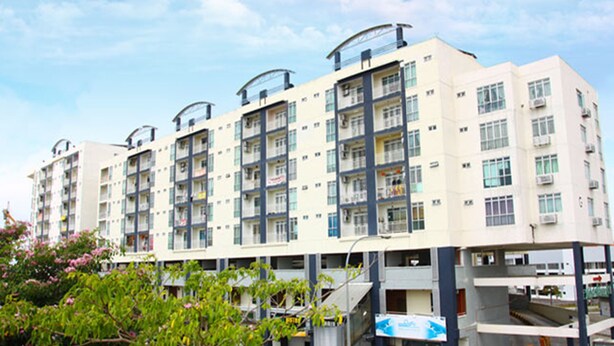 A multi-story residential building with balconies, large windows, and a flat roof.