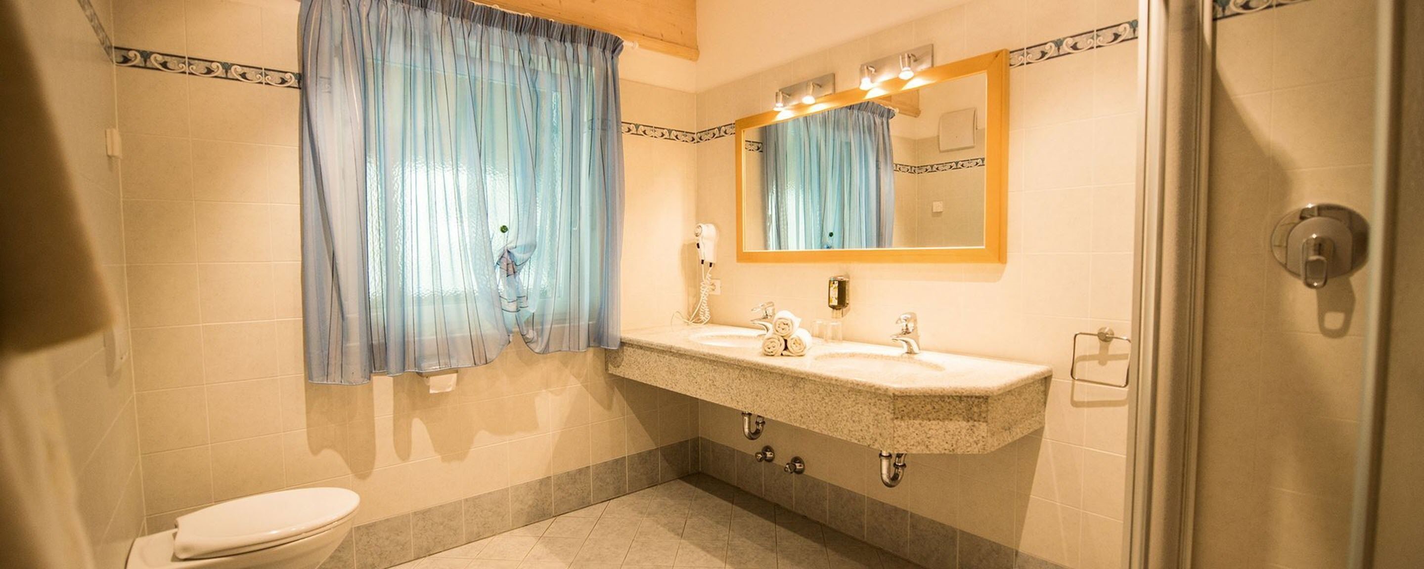 A bathroom with a toilet, a sink with a mirror, and a shower area.