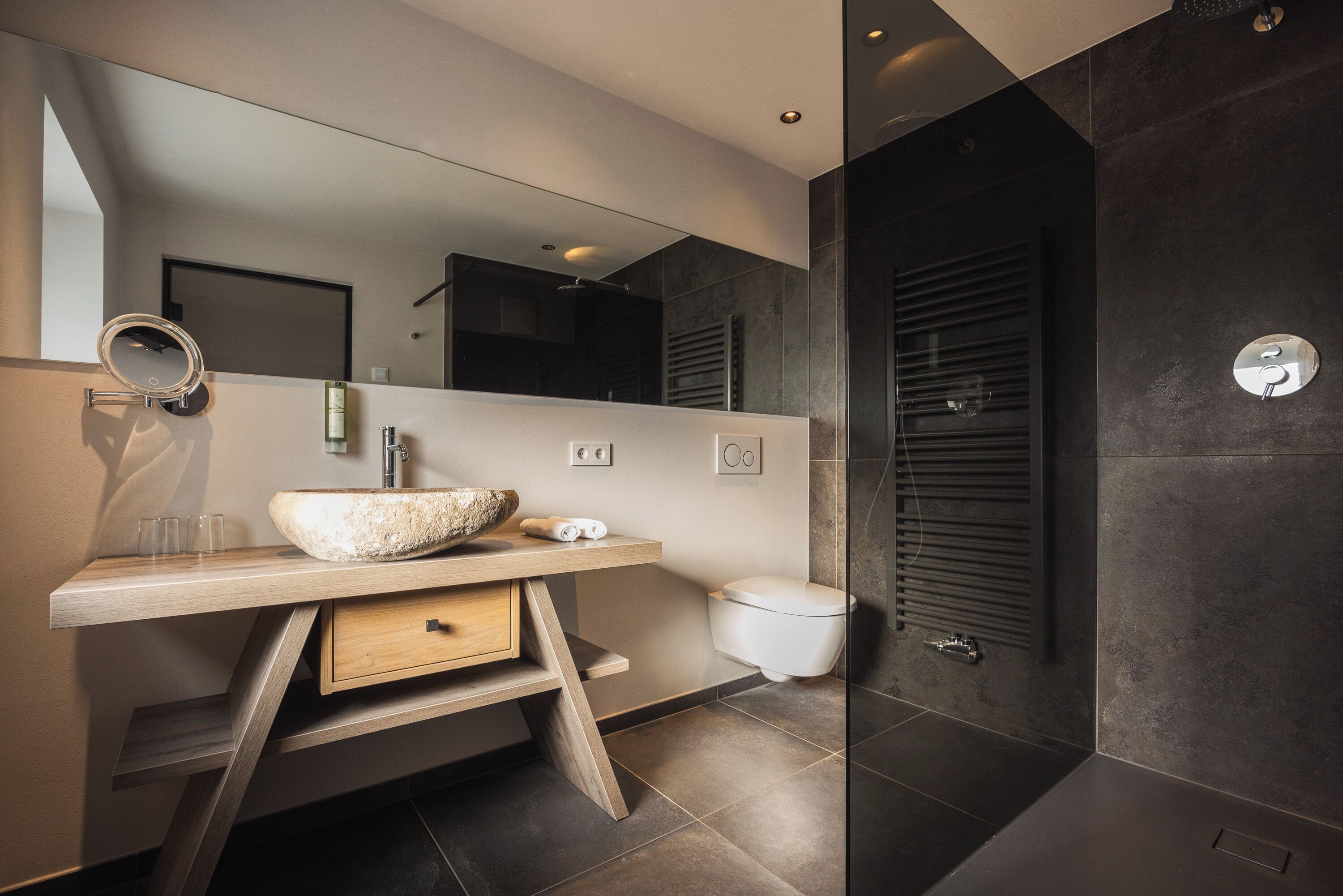 A modern bathroom with a large vessel sink, a mirror, and a walk-in shower.