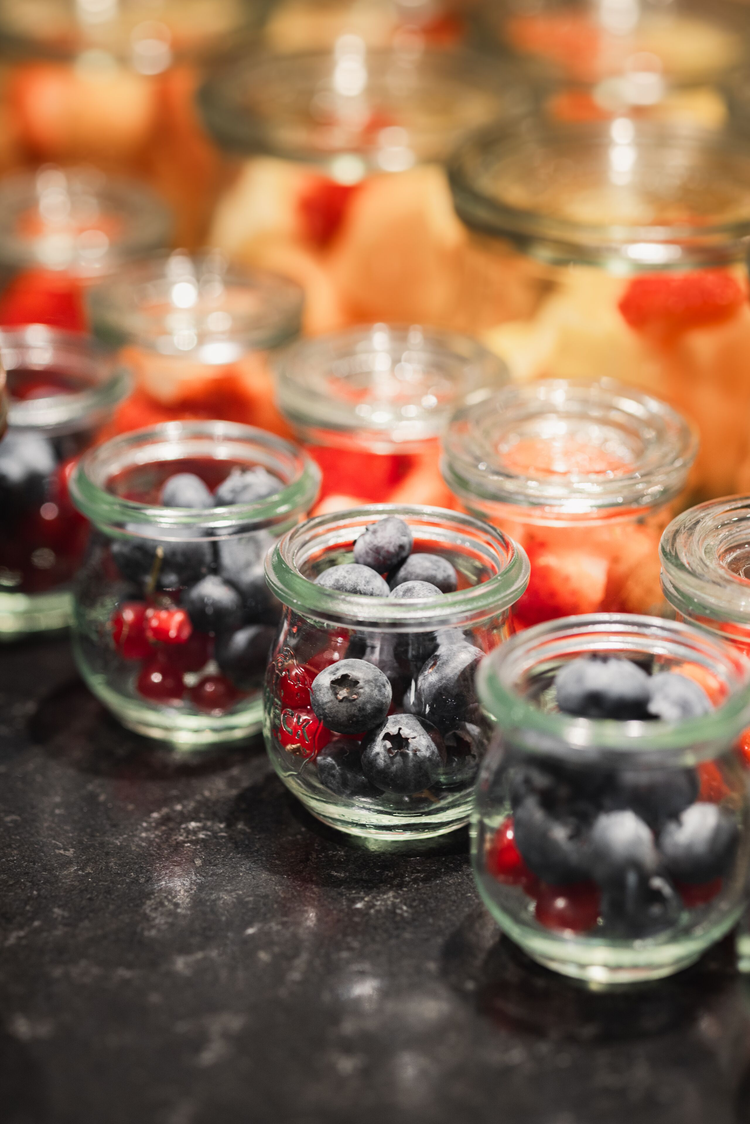 A close-up of glass jars filled with blueberries and red currants.