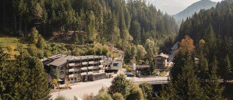 A hotel with a modern design, located in a mountainous area with dense forests.