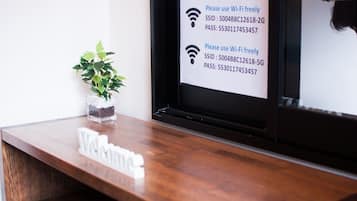 A reception desk with a sign indicating Wi-Fi access and a plant on the left.