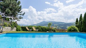 Une piscine avec des chaises longues et une vue sur les montagnes.