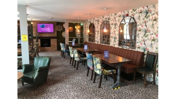 A restaurant with a patterned carpet, wooden tables, and floral wallpaper. - The Crown Hotel (Hailsham)
