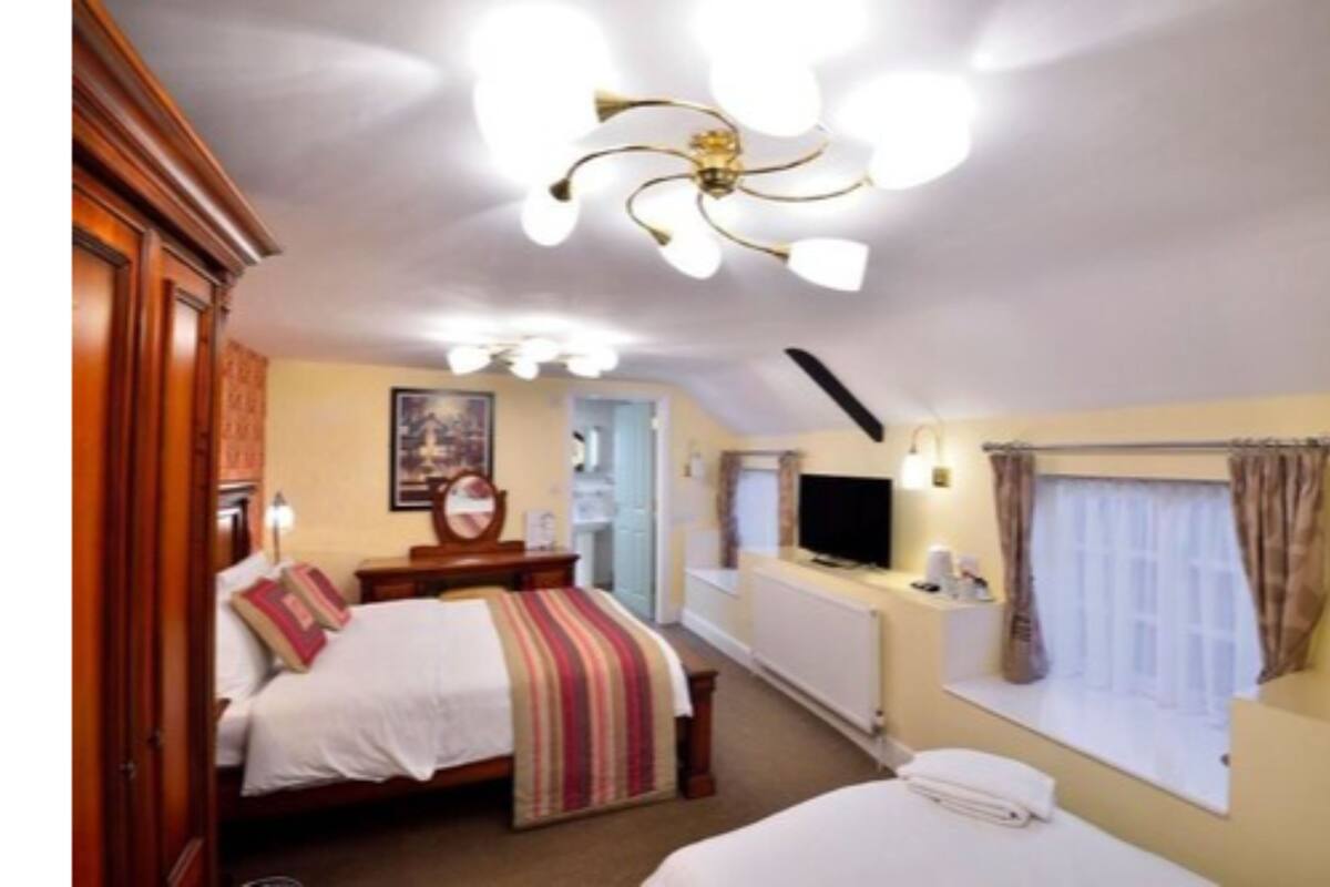 Une chambre à coucher avec un lit, une table de chevet, une télévision et une fenêtre avec des rideaux.