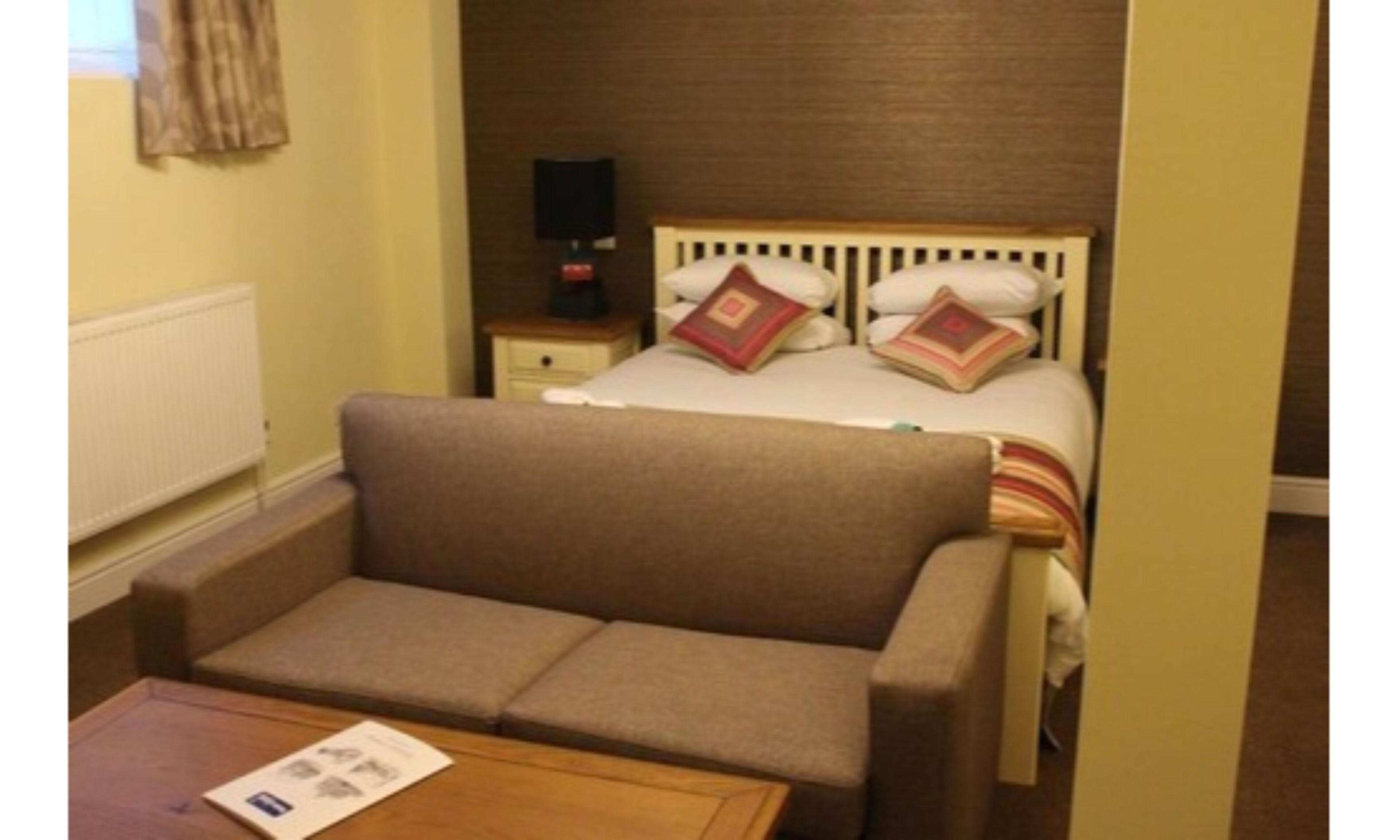 Een hotelkamer met een enkel bed, een slaapbank, een nachtkastje en een televisie.