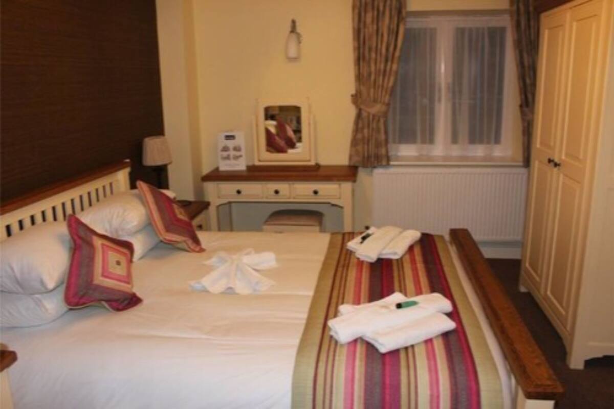 Une chambre d’hôtel avec un lit, une table de chevet et une armoire.
