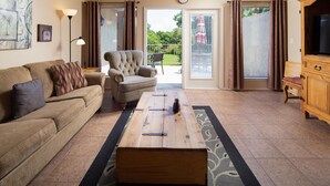 A living room with a sofa, armchair, coffee table, and a TV cabinet.