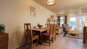 A dining area with a wooden table and chairs, a small rug, and a ceiling fan.