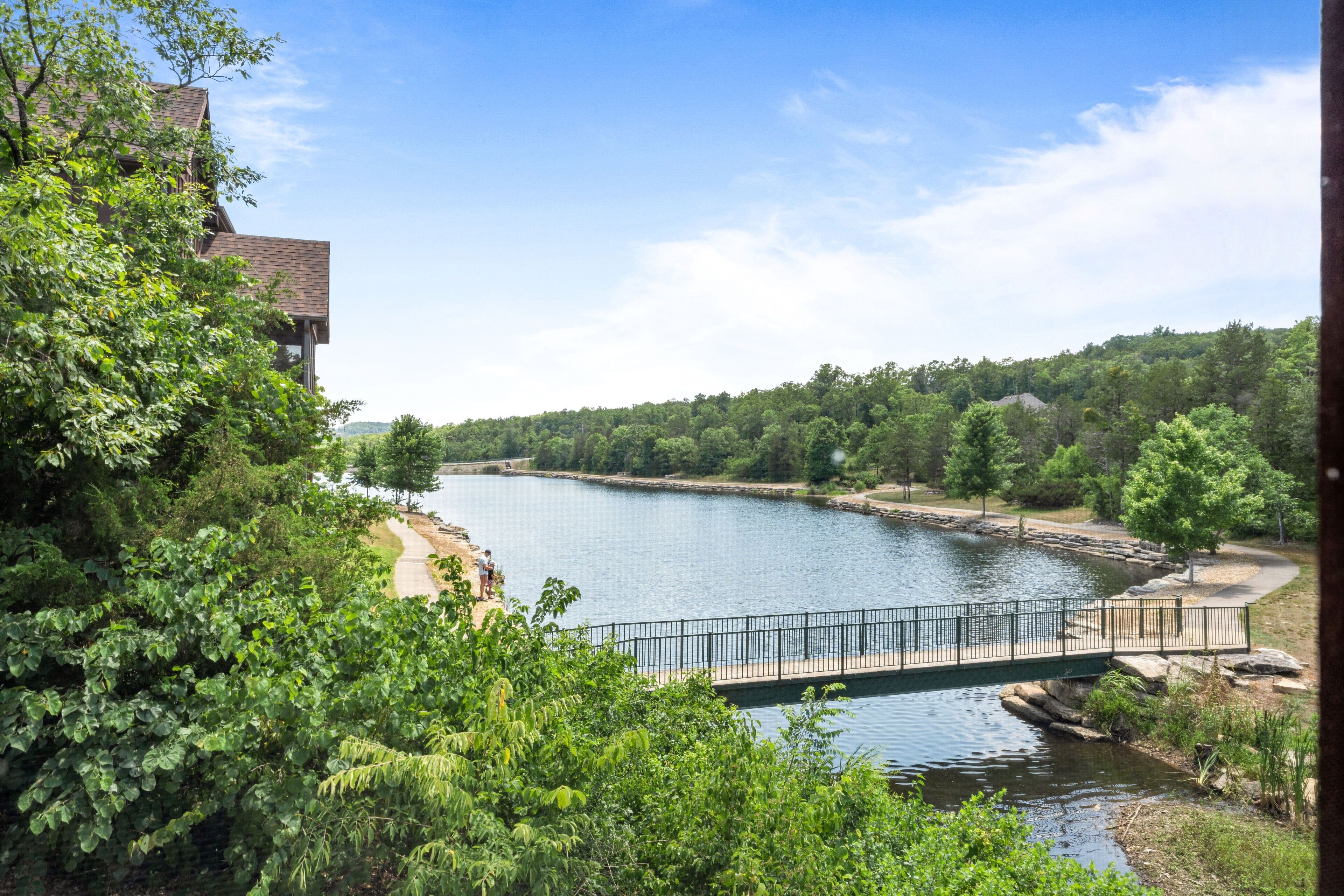A river with a bridge, surrounded by trees and a building.