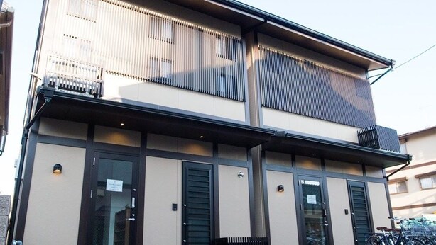 A modern building with a flat facade, large windows, and a bike parking area. - Guest House One More Heart at NARA BI - Hostel (Nara)