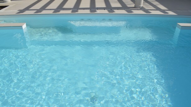 Ein klarer, blauer Swimmingpool mit modernem Design, der eine gerade Kante und eine saubere, ungeordnete Oberfläche aufweist.