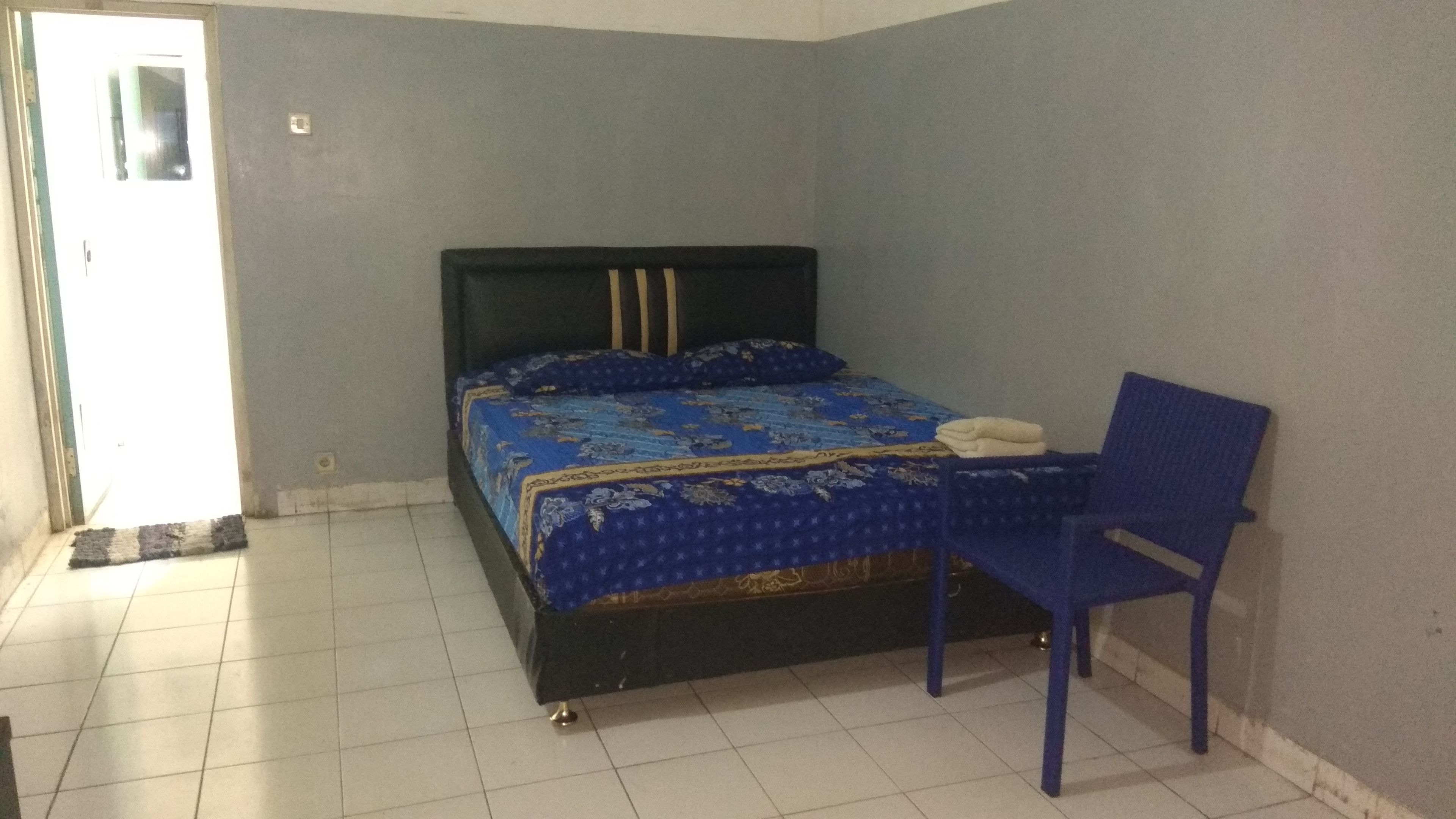 A bedroom with a bed, a chair, and a door.