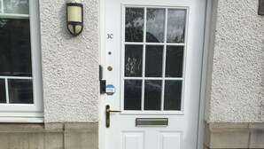 Une porte d’entrée blanche avec un panneau de verre, une boîte aux lettres et un pot de fleurs.