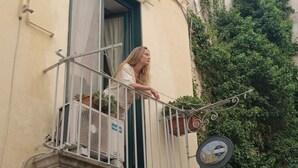 Un balcon avec une balustrade en métal, un pot de fleurs et une plaque indiquant des numéros.