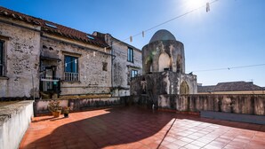 Une terrasse sur le toit avec un sol carrelé, un bâtiment surmonté d’un dôme et un ciel d’un bleu limpide.