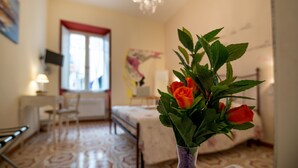 Une chambre d’hôtel avec un lit, un bureau, une chaise, une lampe et une fenêtre dotée d’un cadre rouge.