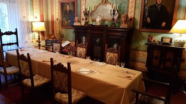 Ein Esszimmer mit einem langen Tisch, gedeckt für eine Mahlzeit, umgeben von Stühlen.